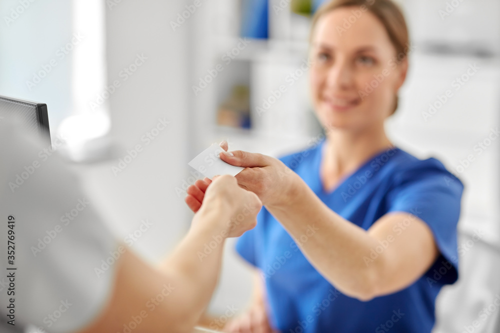 Fototapeta premium medicine, people and healthcare concept - close up of patient giving tag to doctor or nurse at hospital