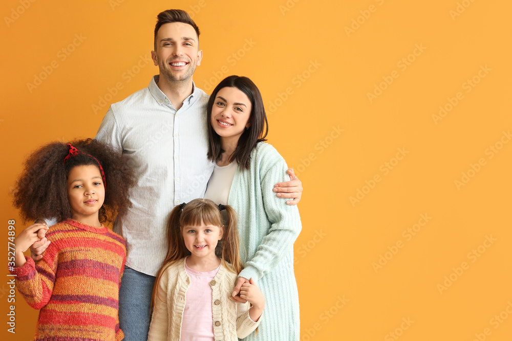 Happy couple with little adopted children on color background
