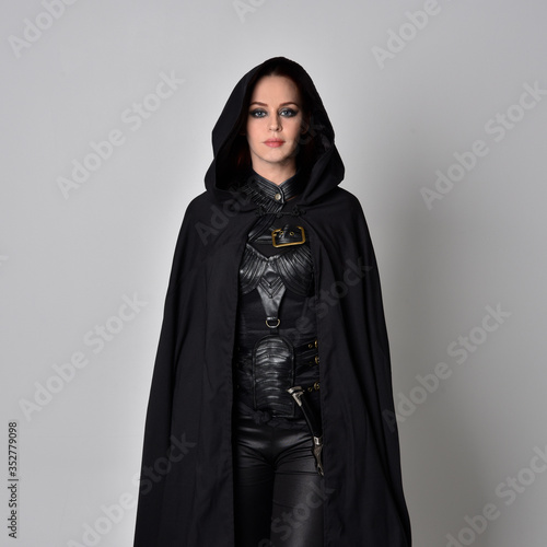 Quadro em tela Close up fantasy portrait of a woman with red hair wearing dark leather assassin costume with long black cloak