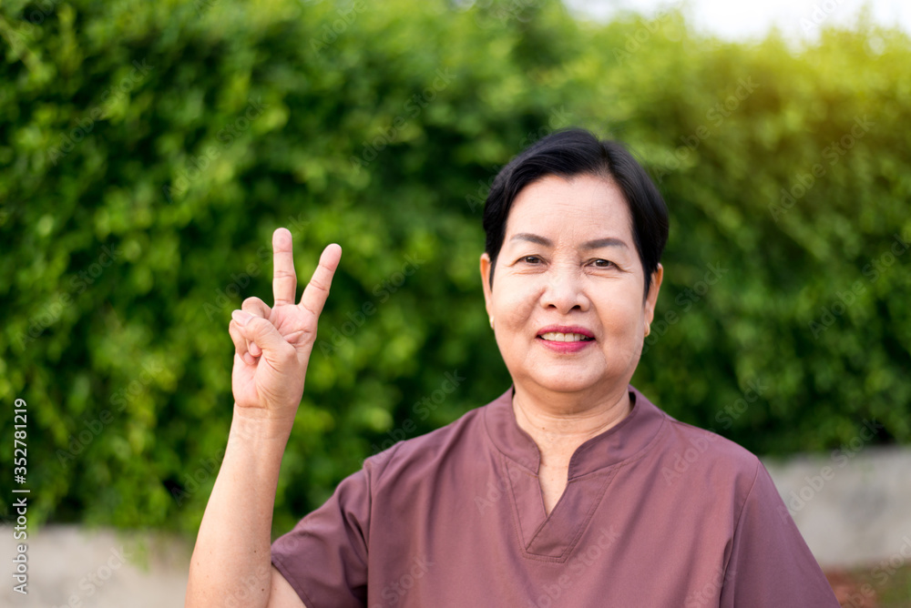 Mature asian woman standing and showing 2 fingers,Senior care insurance concept Mature asian woman standing and showing 2 fingers,Senior care insurance concept