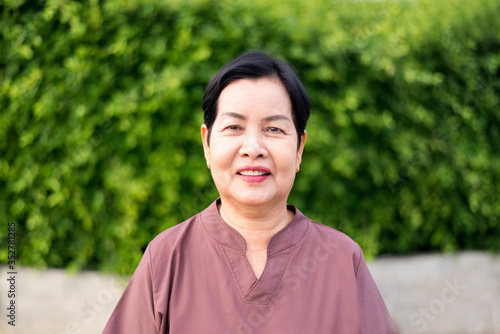 Mature asian woman standing at public park,Happy and smiling,Senior care insurance concept