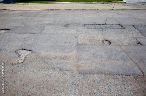 Fragment starej, uszkodzonej asfaltowej jezdni.