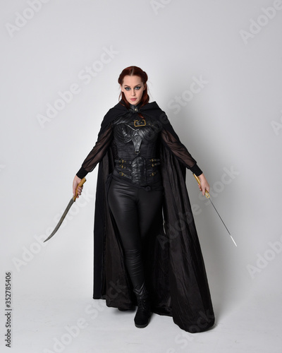 Canvas Print fantasy portrait of a woman with red hair wearing dark leather assassin costume with long black cloak