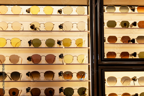 A selection of sunglasses of different shapes, colors and sizes on a shop window. Front view.