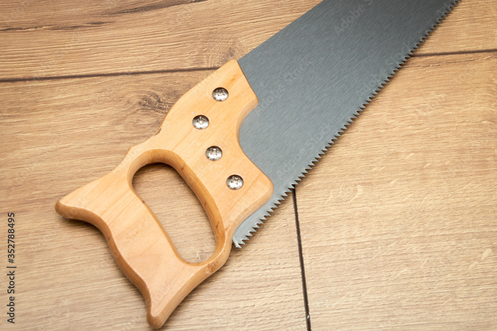 Hand saw with wooden handle on a wooden background. close-up. Hand saw with wooden handle on a wooden background. close-up.