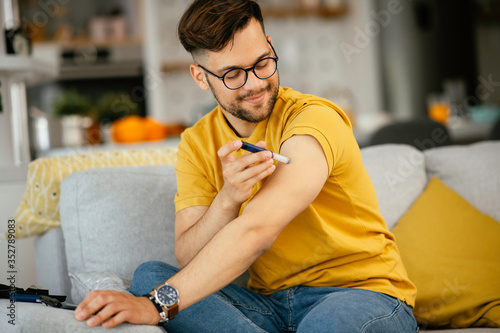 Young man giving himself an insulin shot at home 