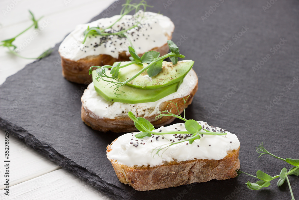 Healthy sandwiches with avocado , cream cheese and micro green. Vegan sandwiches, vegan food, healthy eating. Template with space for text , black and white background Healthy sandwiches with avocado , cream cheese and micro green. Vegan sandwiches, vegan food, healthy eating. Template with space for text , black and white background