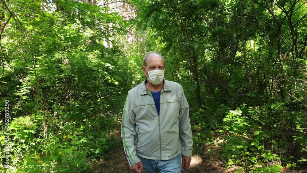 an elderly man in a protective mask walks in the Park, a walk in the fresh air after quarantine, a precautionary measure against the virus an elderly man in a protective mask walks in the Park, a walk in the fresh air after quarantine, a precautionary measure against the virus