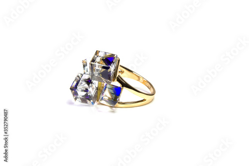 a gold ring with large square and transparent stones rests on a white background.