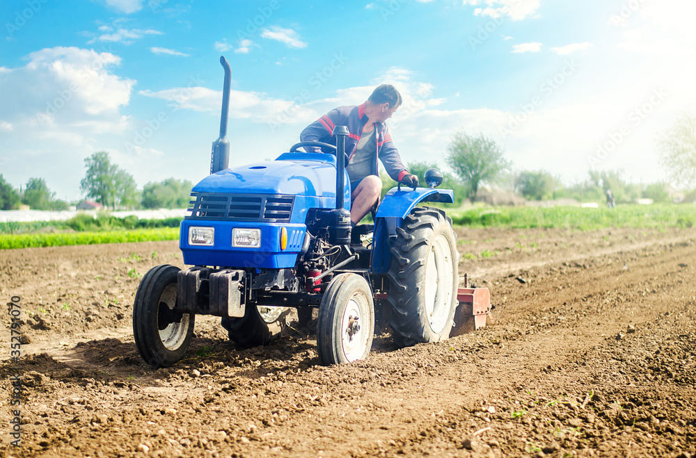 Farmer on a tractor with milling machine loosens, grinds and mixes soil. Loosening the surface, cultivating the land for further planting. Farming and agriculture. Cultivation technology equipment Farmer on a tractor with milling machine loosens, grinds and mixes soil. Loosening the surface, cultivating the land for further planting. Farming and agriculture. Cultivation technology equipment