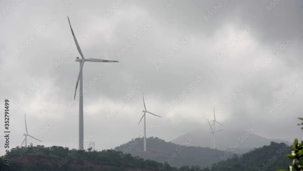 Windmills technology ecological energy on mountains in slow motion spinning. Wind turbine blade propeller rotate slowly at high hills farm location with trees. Windmills technology ecological energy on mountains in slow motion spinning. Wind turbine blade propeller rotate slowly at high hills farm location with trees.