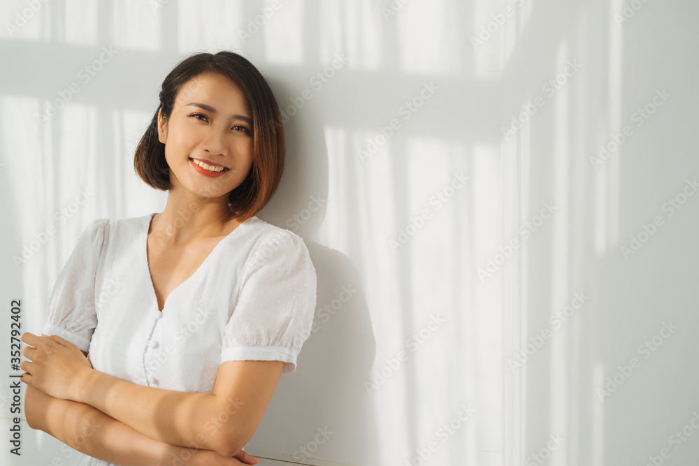A young beautiful is standing against the wall, the sunlight is beautifully falling. Shade from the blinds. A young beautiful is standing against the wall, the sunlight is beautifully falling. Shade from the blinds.