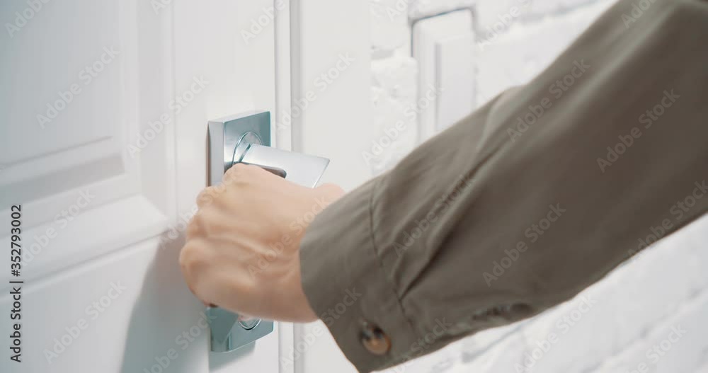 Close up of female hands opening a white door with a metal handle Close up of female hands opening a white door with a metal handle