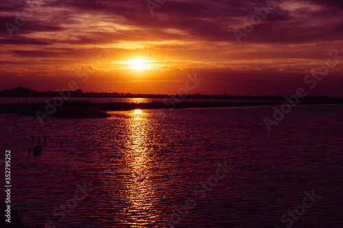 Saline di Cervia Natural Park and Wildlife Reserve at sunset  a wildlife and bird sanctuary  perfect for birdwatching. Sun going down above water with rays reflections.