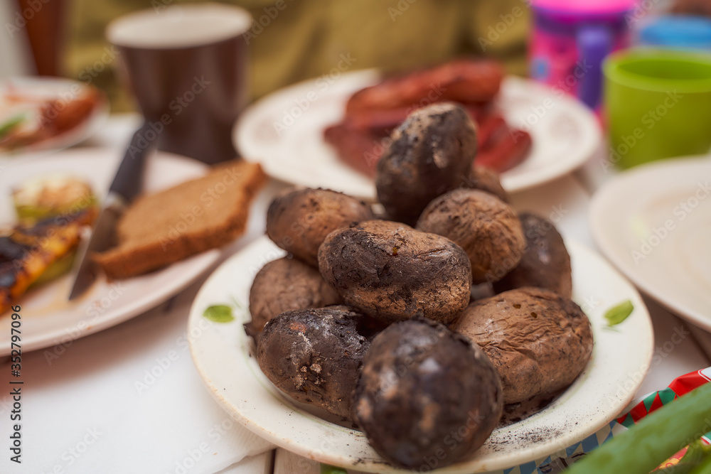 A few pieces of baked potatoes on the fire. Lying on a white plate A few pieces of baked potatoes on the fire. Lying on a white plate