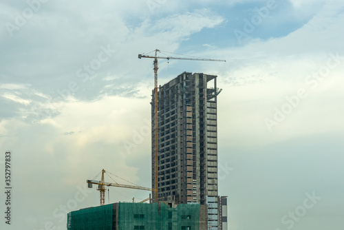 Building under construction  Condo construction  Building site with yellow cranes  and blue sky background.