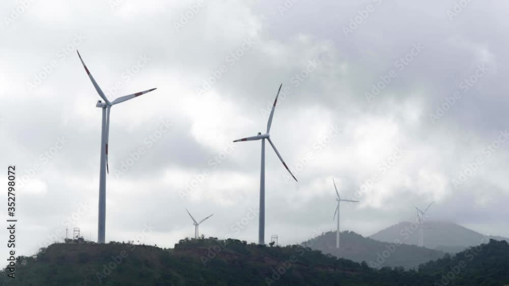windmills alternative ecological energy on mountains in slow motion spinning. Wind turbine blade propeller rotate slowly at high hills farm location with trees. windmills alternative ecological energy on mountains in slow motion spinning. Wind turbine blade propeller rotate slowly at high hills farm location with trees.