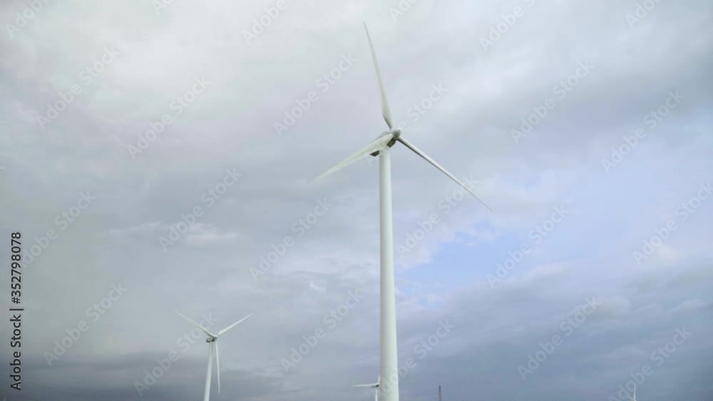 Single wind turbines windmill with sky seen from pov of a moving hand held slow motion at daytime. Renewable energy blades spins around and generating green energy. Single wind turbines windmill with sky seen from pov of a moving hand held slow motion at daytime. Renewable energy blades spins around and generating green energy.