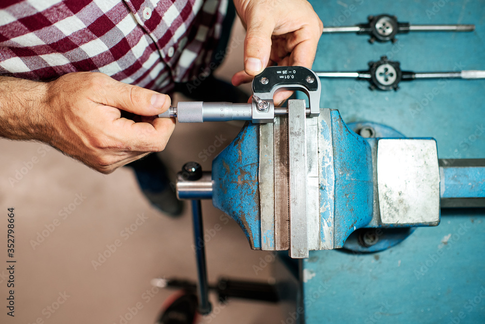 a worker measures with a micrometer in his workshop a worker measures with a micrometer in his workshop