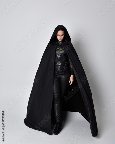 Foto fantasy portrait of a woman with red hair wearing dark leather assassin costume with long black cloak