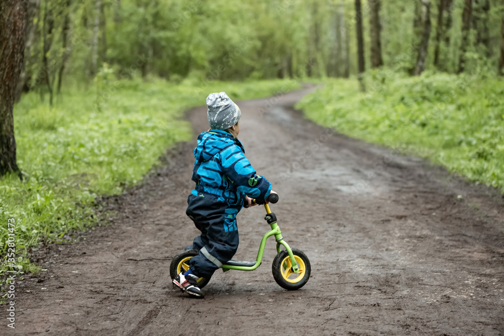 Little boy riding runbike on the forest road