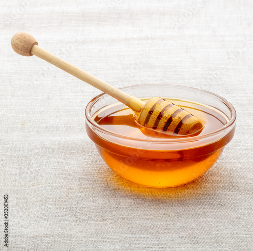 miel de abejas en cuenco de cristal con cuchara de madera. bee honey in glass bowl with wooden spoon.