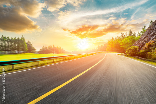 Fast moving asphalt highway and green forest at sunset. © ABCDstock