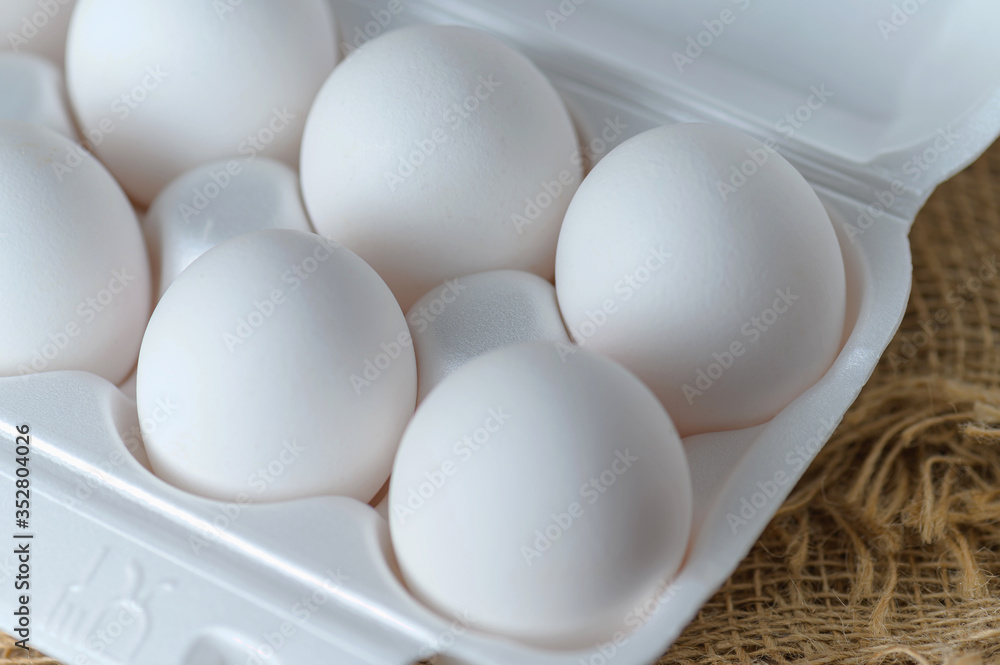 White raw chicken eggs in a plastic tray close-up. Chicken eggs background. White raw chicken eggs in a plastic tray close-up. Chicken eggs background.