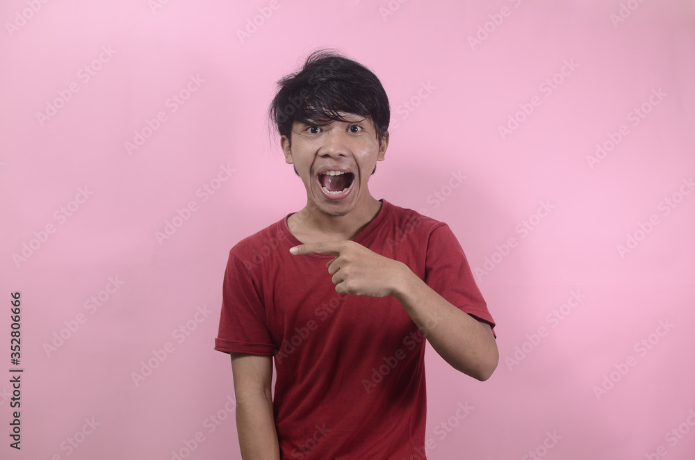 Asian man's shocked face with empty space. Asian men wearing red t shirts isolated on a pink background