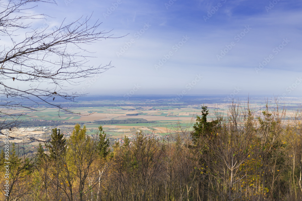 Krajobraz nizinny, widok ze zbocza góry Ślęży , z koronami drzew na pierwszym planie