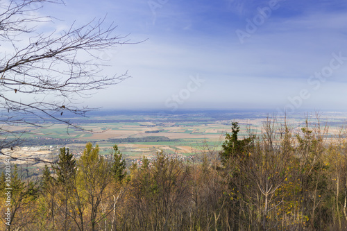 Krajobraz nizinny, widok ze zbocza góry Ślęży , z koronami drzew na pierwszym planie © Joanna