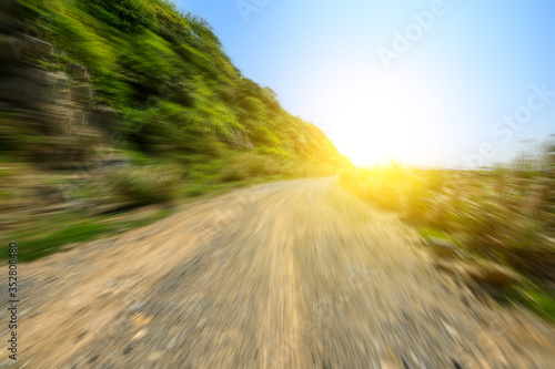 Motion blurred gravel road and mountain landscape by the sea.