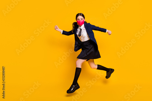 Full body profile side photo of crazy high school student girl jump run copyspace wear black blazer jacket skirt long socks medical mask isolated over yellow color background