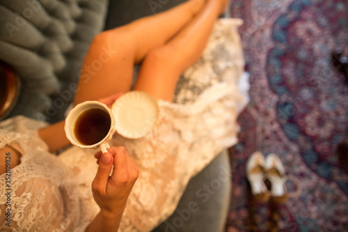 beautiful brunette bride sitting on sofa and drink the coffee