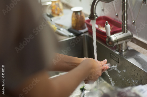 
girl washes hands in the kitchen. Girl washes her hands while cooking. Female hands under the tap in the kitchen