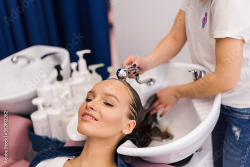 Young woman in a salon getting washed her hair with shampoo
