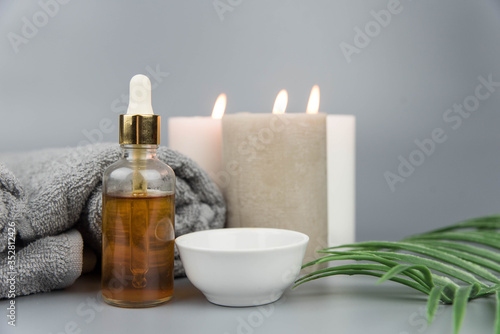 Towel with aromatic candles and bottle with natural organic oil essence serum. Aromatherapy and beauty. Concept set of harmony  balance and meditation  spa  massage  relax  beauty spa treatment.