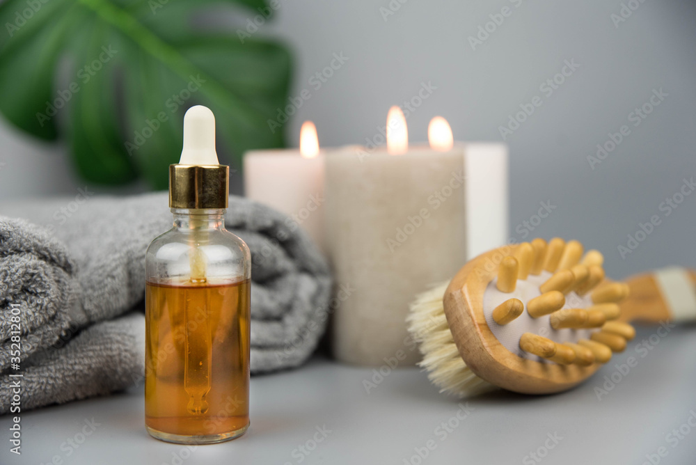 Towel with aromatic candles, bottle with natural organic essential oils and massage brush. Aromatherapy and beauty. Concept set of harmony, balance and meditation, spa, relax, beauty spa treatment.