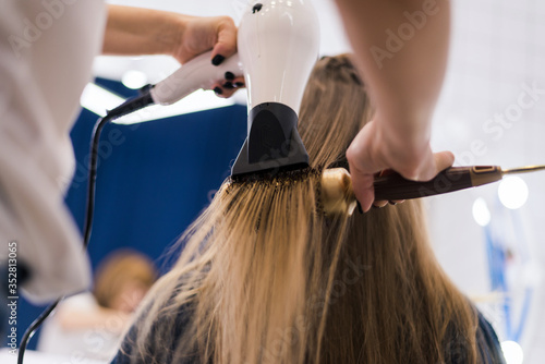 Hair stylist making ringlets to woman. Hairdresser working with beautiful woman hair in hairdressing salon.