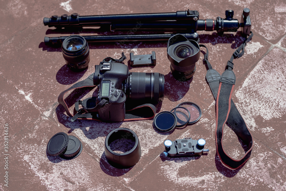 Obraz premium Flat lay photography of camera gear including camera, lenses, straps and other accessories on the ground