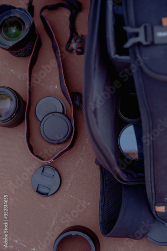 Flat lay photography of camera gear including camera, lenses, straps and other accessories on the ground