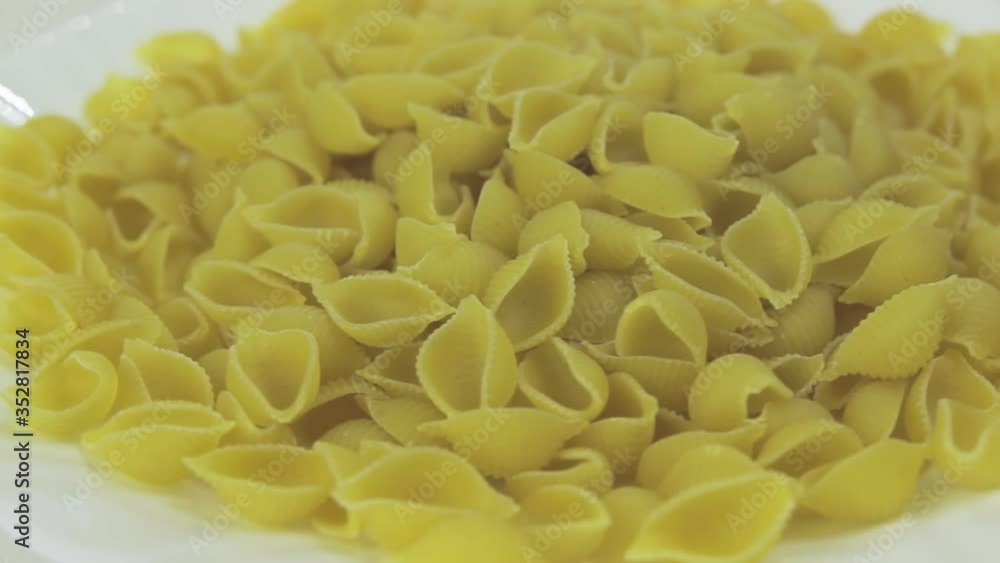 Rotation of a full plate of uncooked conciglia. Pasta on a white porcelain plate Rotation of a full plate of uncooked conciglia. Pasta on a white porcelain plate