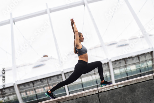 Beautiful athletic girl in sportswear practicing yoga outdoors. A woman doing high lunge. Healthy habits concept