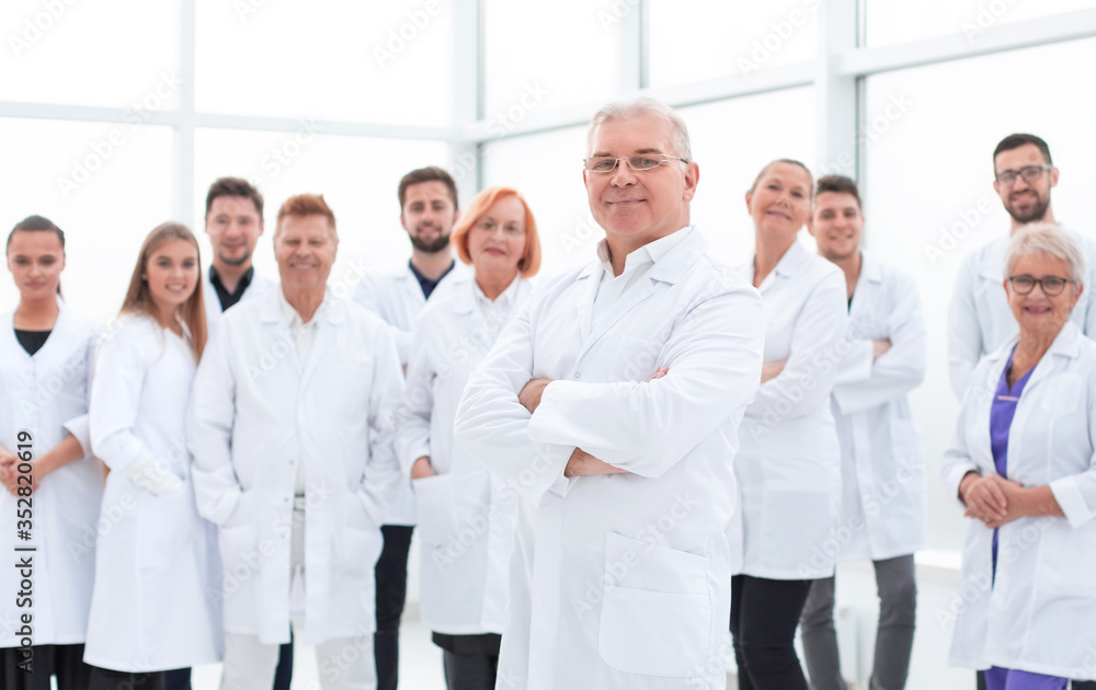 senior doctor standing in front of a group of medical staff. senior doctor standing in front of a group of medical staff.