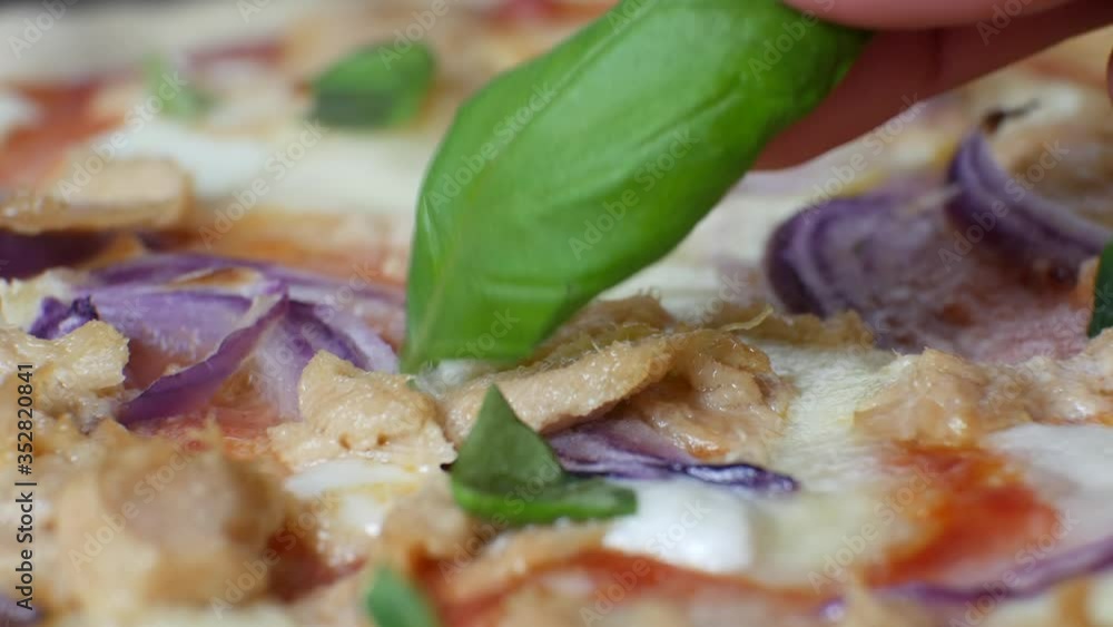 Fresh homemade Italian pizza adding basil on the top, extreme close up, real time 4K Fresh homemade Italian pizza adding basil on the top, extreme close up, real time 4K