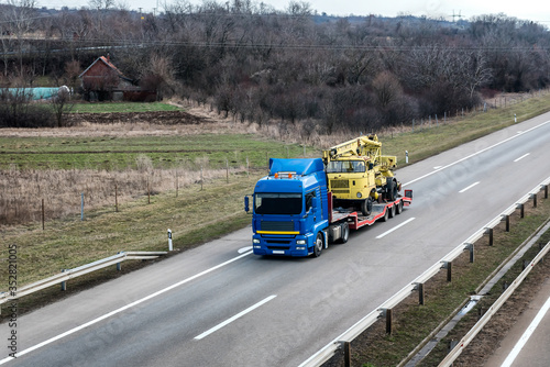 Wallpaper Mural Transportation Tow truck or Flatbed truck on a highway carrying a construction machine to a site under a beautiful sky on a highway. Tow transportation concept Torontodigital.ca