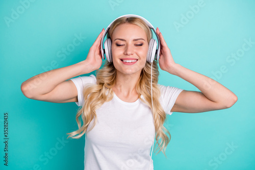 Portrait of pretty content woman listen stereo music headset have holiday summer weekend isolated over teal color background