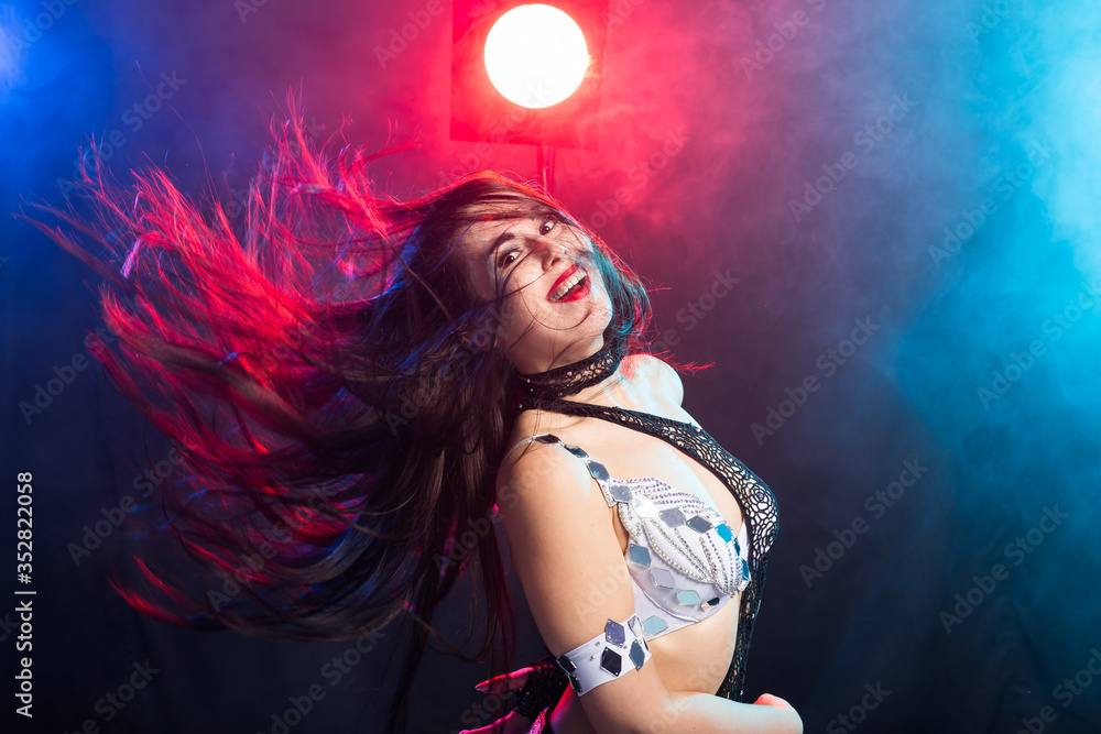 Naklejka premium Young woman belly dancer in exotic dress with gold, dancing tribal fusion dance in studio.