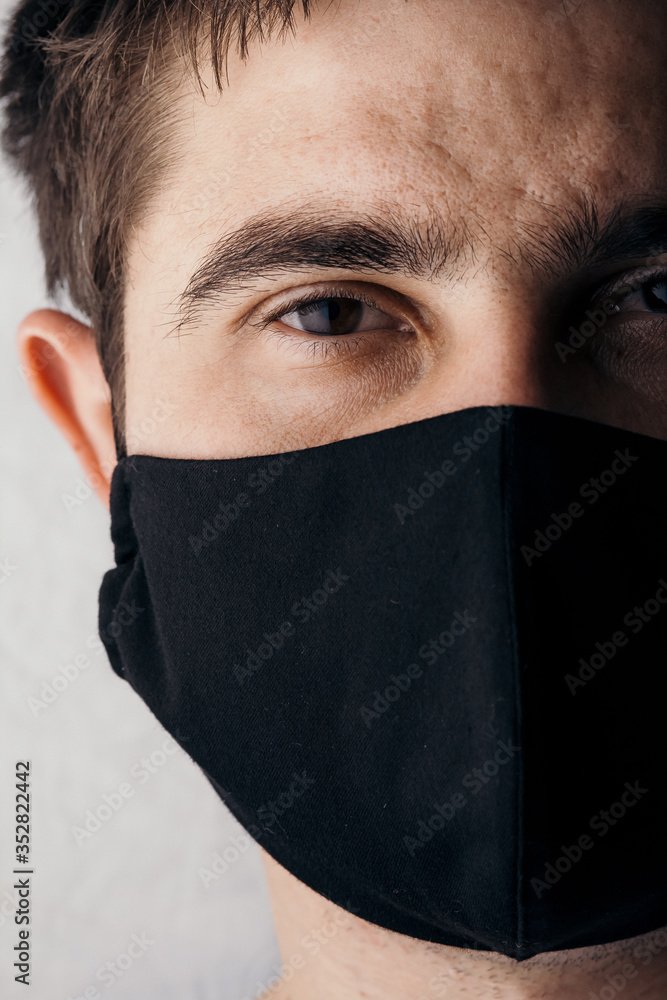 half of head of serious young man face wearing black protectivemask on studio background, concept of desease, exhausted look of human half of head of serious young man face wearing black protectivemask on studio background, concept of desease, exhausted look of human