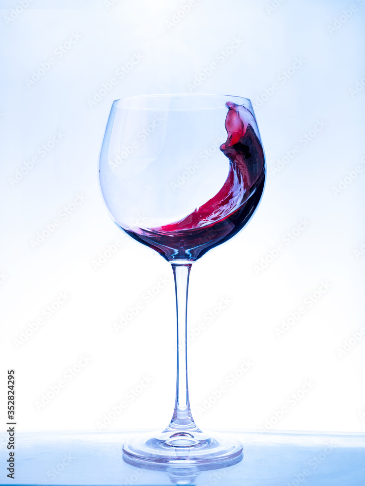 Red wine splashing a wave in a glass. Red wine splashing a wave in a glass.